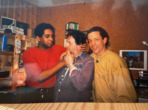 Farbfoto, frühe 1990er Jahre: Ronnie Burrage (links) hält Harry Pepl im Spaß die Hand vor den Mund, rechts John Purcell; Korkwand, Regale mit Tonbändern und Geräten im Heimstudio in Hernstein. Von links nach rechts: Ronnie Burrage, Harry Pepl und John Purcell.