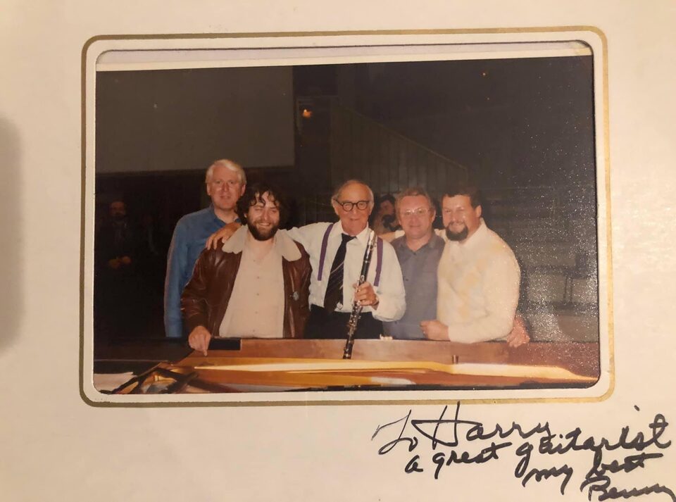 Farbabzug im Passepartout aus Berlin, November 1980: die Band in der Kleidung der Probe am Flügel auf der Bühne der Philharmonie, von links Don Haas, Harry Pepl, Benny Goodman mit der Klarinette, Peter „Fifi“ Witte und Charly Antolini. Darunter hat Goodman das Foto für Pepl signiert: „To Harry, a great guitarist, my best, Benny“.
