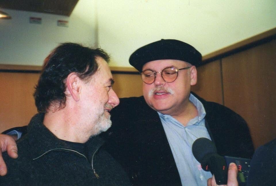 Farbfoto mit Datumsaufdruck 2001: Harry Pepl und Karl Ratzer (mit Baskenmütze) Arm in Arm, rechts ein Reportermikrofon. Nach Angaben der Familie aus der Zeit, als Ratzer sich um die Professur für Jazzgitarre an der Kunstuniversität Graz bewarb; er unterrichtete dort 1999 bis 2003 als Gastlehrender. Links Harry Pepl, rechts Karl Ratzer.