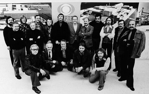 Group picture of the ORF Big Band (big band of Austria's public broadcaster) with eighteen musicians in front of the ORF logo and large architectural pictures, 1970s. Harry Pepl was the band's guitarist and soloist from 1971 to 1977; the names of those pictured are not recorded.